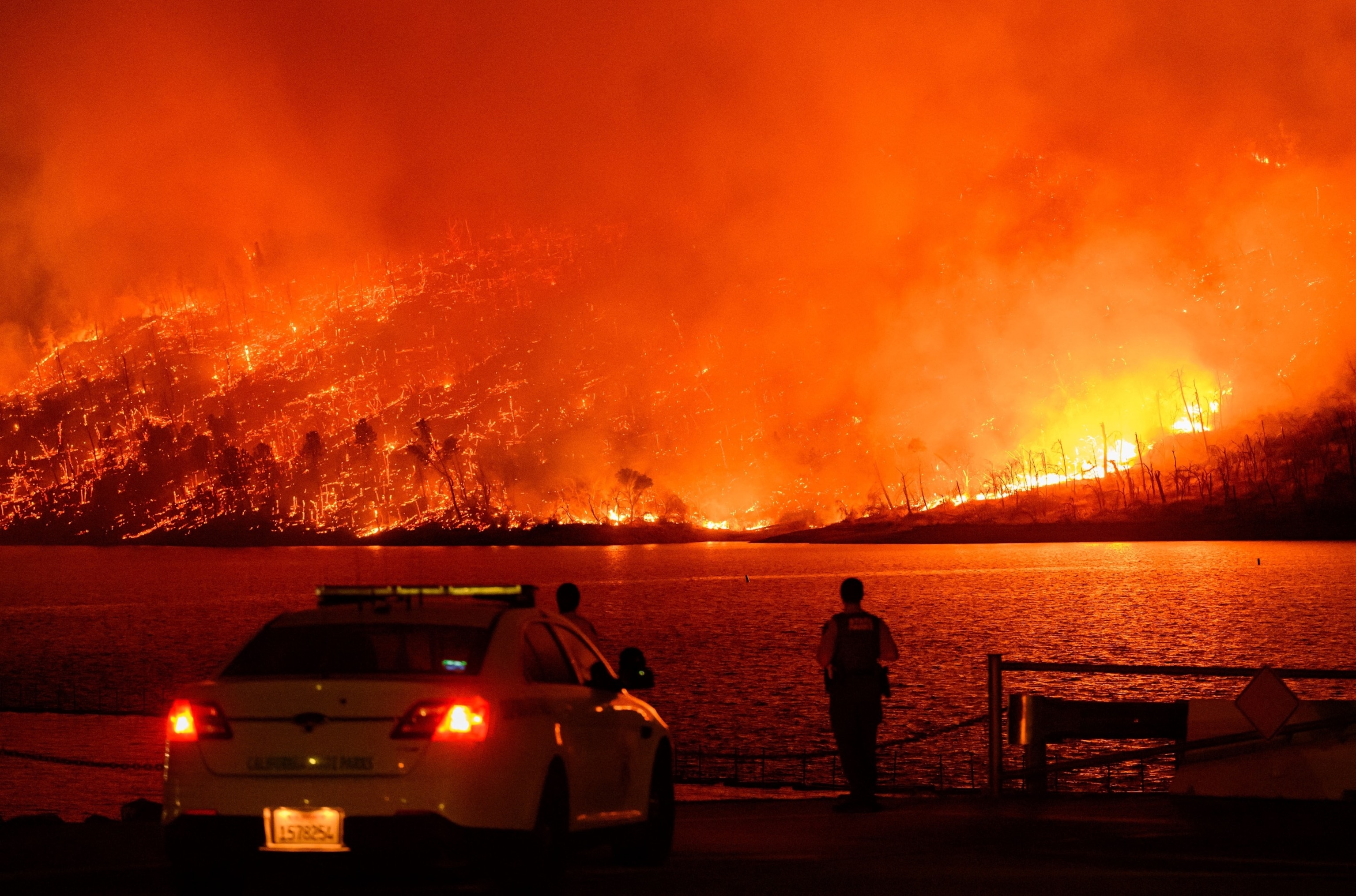 PHOTO: Law enforcement members watch as the Thompson fire burns over Lake Oroville in Oroville, California on July 2, 2024.