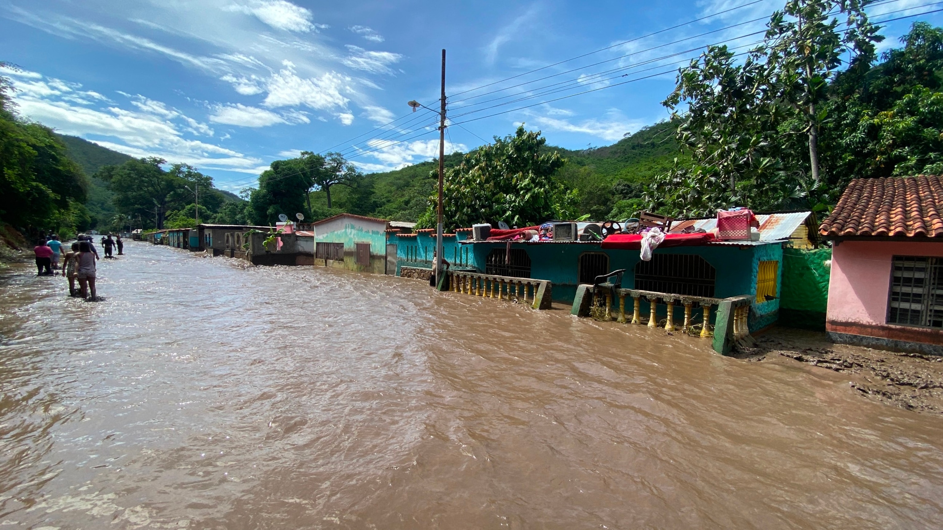 PHOTO: People stand outside their flooded homes after a river swelled due to heavy rains following the passage of Hurricane Beryl on the road from Cumana to Cumanacoa, Sucre State, Venezuela, on July 2, 2024.